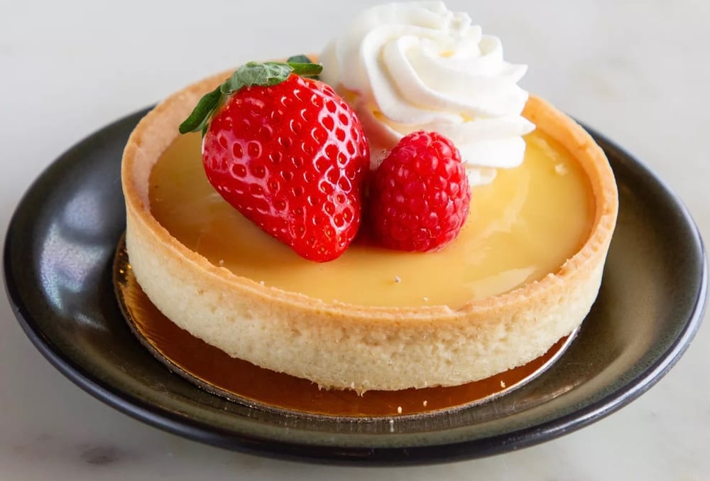 Lemon tart topped with strawberry, raspberry and whipped cream